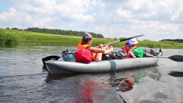 Two woman with boy row in inflatable canoe on Tvertsa river 