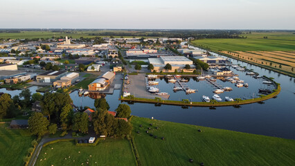 Aerial drone view of harbor, marina and industrial area in Steenwijk, The Netherlands. Company buildings next to canal surrounded by nature farmland meadow landscape captured from above. 