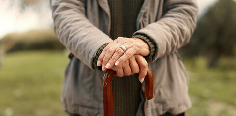Senior cane, hands and person in nature for walking, relax and in a park for peace. Closeup, standing and an elderly woman in a garden or natural environment for wellness with a stick for support