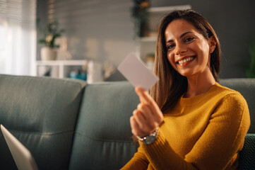 Woman looking into the camera while posing with a credit card in her hand