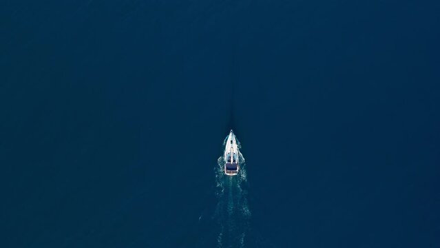 White sailing yacht in the middle of the boundless sea with calm water. Aerial top down view