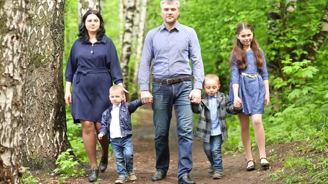 Family of five members with girl and two boys walk on path together