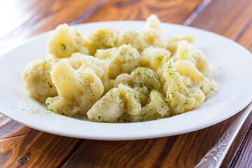 Cooked cauliflower, steamed, in a plate with spices .
