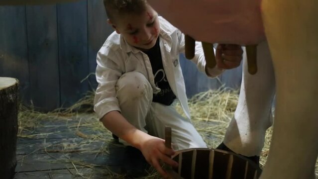 Boy with painted face, milking the fake cow in the barn