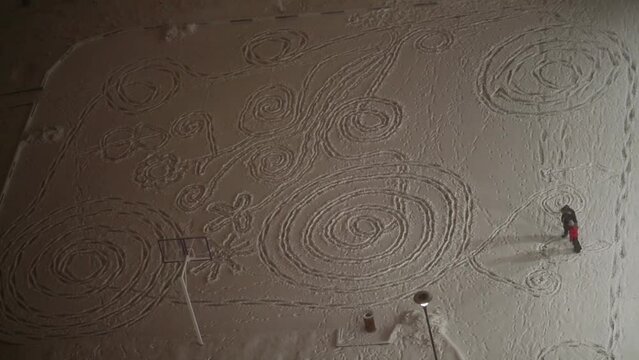 Two people on a snowy field with patterns trampled by the feet