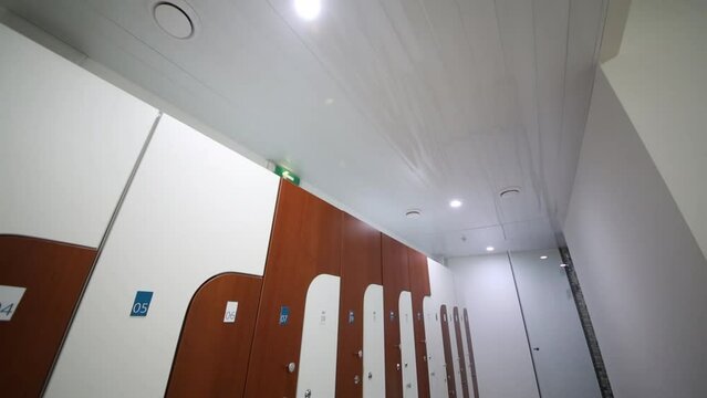 Locker room with white and brown cabinets in modern sports club