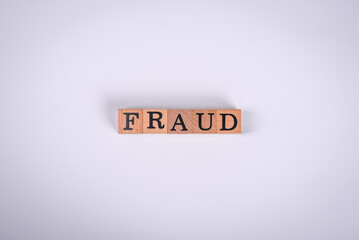 The inscription Fraud inspection made of wooden cubes on a plain background