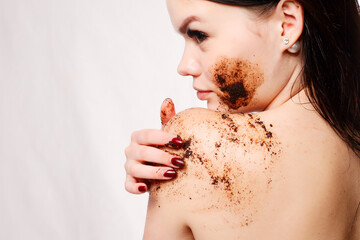 Brunette woman cleans the skin of the body coffee scrub