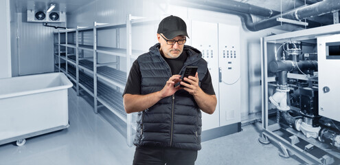 Man inside refrigeration storage. Worker with phone in his hands. Guy in empty refrigerated...