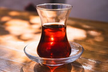 Tea in a glass cup on the table. Turkish Tea and slim glass cup. Real Turkish Tea, red in color. - obrazy, fototapety, plakaty