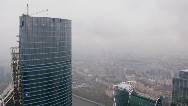 Skyscraper under construction and roof of other against cityscape 