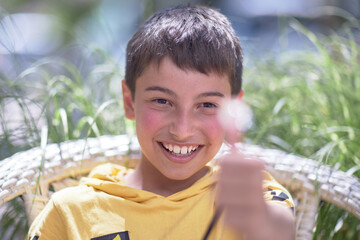 portrait of a child, burnt skin in the sun, a 10-year-old brunette boy in a summer cafe. Drinks a mojito and eats a hamburger