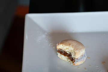 Close up view of an  alfajor with a bite sitting on square plate