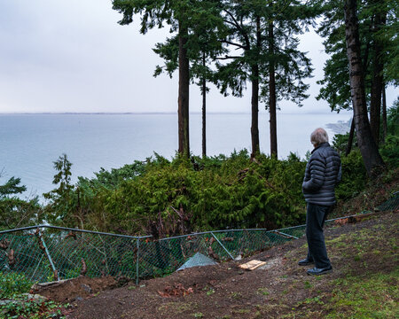 Title: Bystander overlooking large embankment collapse after record amounts of rainfall in Crescent Beach, British Columbia, Canada.