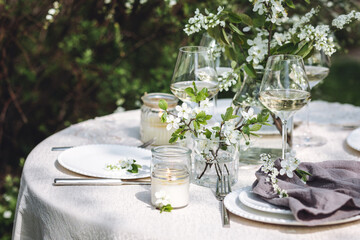 Rustic elegant eco friendly zero waste trendy wedding reception table decor with fresh spring apple cherry flowers in bloom. Beautiful marriage decoration, holiday event outdoors in the family garden