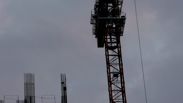 People assemble tall crane against cloudy sky at evening.