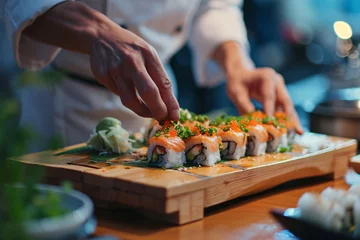 Fotobehang a person's hand placing sushi on a wooden board © Galina