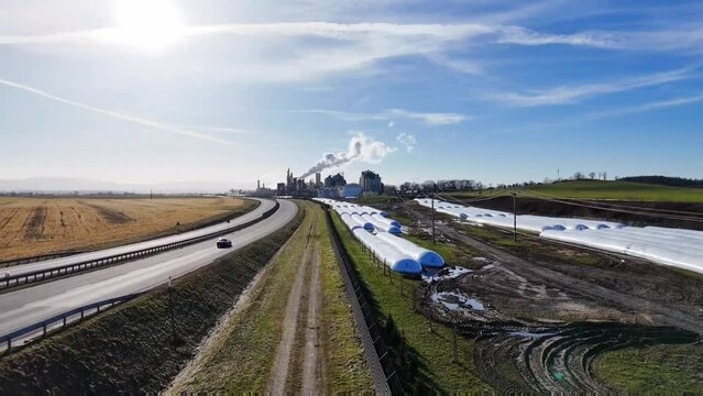 Polna droga wzdłuż ogrodzenia i autostrady, zakład, firma, dym z komina, widok z drona.
