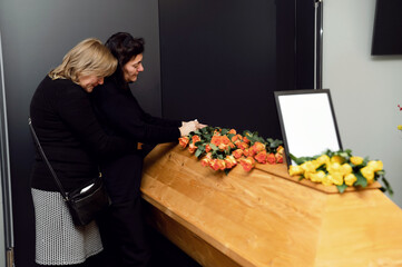 funeral ceremony. a widow and family members are crying near the coffin. family's longing for the...