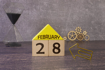 Cube shape calendar for February 28 on wooden surface with empty space for text.