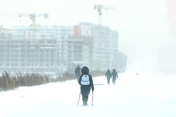 Group of People Walking Across Snow Covered Field in Winter Snowstorm