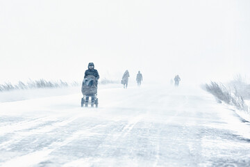 the snowstorm is cold a person has fallen into extreme living conditions is walking along the road through a blizzard in the city, the winter is cold..