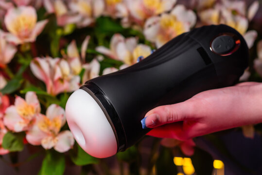 Sex toys for men. An artificial vagina for masturbation in the hands of a girl against a background of flowers. Male massager. Sex shop Adult store