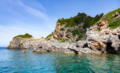 Fototapeta premium Scenic landscape of Island of Corfu, Greece, western shoreline with cliffs and caves at beach and water line of turquoise or deep blue water with breath taking limestone formations