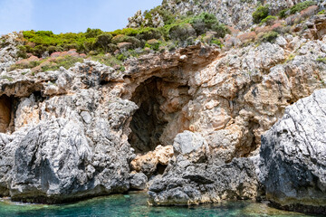 Naklejka na ściany i meble Scenic landscape of Island of Corfu, Greece, western shoreline with cliffs and caves at beach and water line of turquoise or deep blue water with breath taking limestone formations