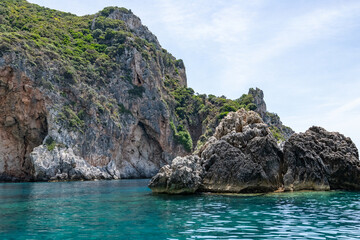 Fototapeta premium Scenic landscape of Island of Corfu, Greece, western shoreline with cliffs and caves at beach and water line of turquoise or deep blue water with breath taking limestone formations
