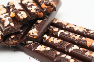 Tasty chocolate with nuts. Chocolate pieces with nuts on white background. Selective focus.