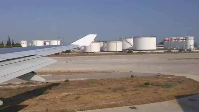 View from airplane on takeoff strip to fuel storage depot with oil and wing