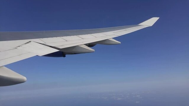 View from window to wing of turning airplane in blue sky