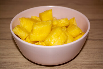 Appetizing yellow sweet pineapple pieces in a pink bowl