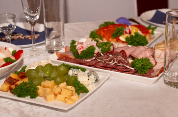 The banquet is festive, beautiful table setting, a table with very tasty meat and cheese dishes.