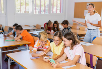 Schoolchildren use mobile phones at the lesson in the classroom