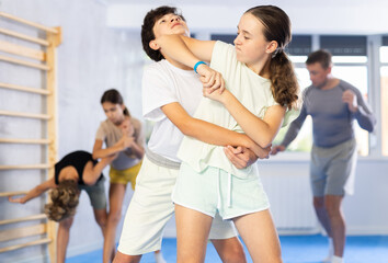 Preteen children pairs learning strength self-defense in the gym