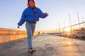 woman dancing in a port at sunset, red hair, smiling