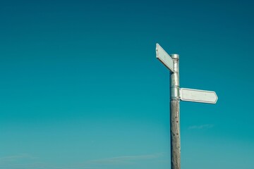 A solitary street sign stands tall against the backdrop of a clear blue sky, marking the intersection of man and nature