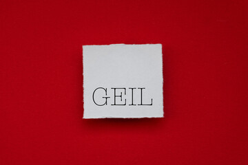 Text - geil -  auf angerissenem Papier auf rotem Tonzeichenkarton