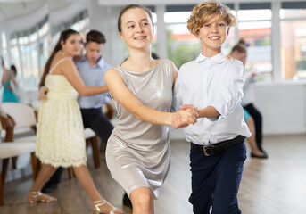 Positive teen boy and girl are dancing contemporary modern discofox in couple during lesson at studio. Leisure activities and hobby for positive people.
