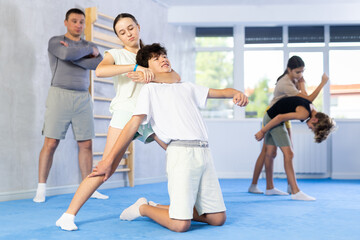 Fototapeta premium Boy and girl practicing self-defense techniques in group at gym