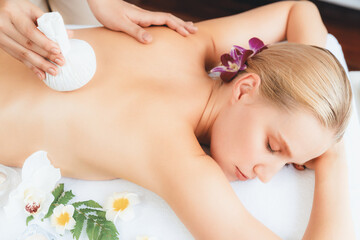 Obraz na płótnie Canvas Hot herbal ball spa massage body treatment, masseur gently compresses herb bag on woman body. Tranquil and serenity of aromatherapy recreation in day lighting ambient at spa salon. Quiescent