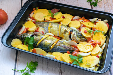 delicious baked mackerel with potatoes and tomato, onion, lemon and spices in a dish prepared to put in the oven