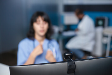 Nurse at hospital is using computer up close to conduct a video chat. In the clinic office, a...