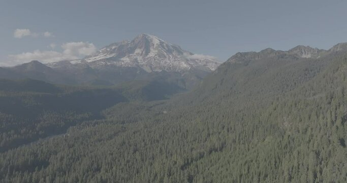 Ungraded wide-angle aerial drone footage of Mount Rainer National Park under hazy blue on a sunny afternoon in Washington State.