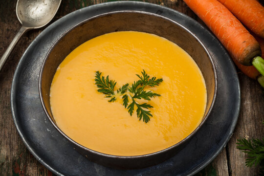 Creamy carrot soup in a rustic bowl with fresh carrots