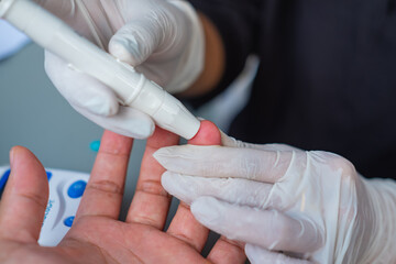 Close up view of medical worker taking patient's blood sample with finger pricking kit. Medical concept. Selective focus.