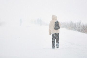 Person Walking in Snow, Wearing White Coat in Winter Snowstorm