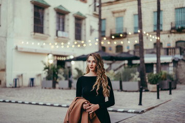 Chica rubia joven posando con vestido negro en la calle